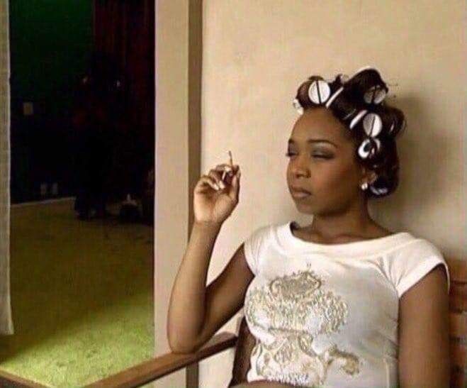 tiffany pollard sitting with a cigarette in her hand and rollers in her hair